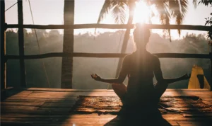 How to meditate properly; a woman meditate on a porch facing sunrise in Bali